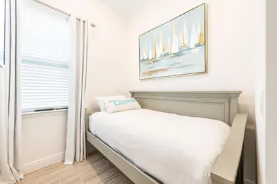 a small bedroom with a bed and a window at Ocean Blue Cottage Near Disney With Margaritaville Resort & Island H20 Waterpark Access - 2971La in Orlando