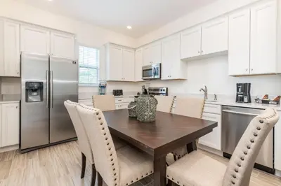 a kitchen with a wooden table and white cabinets at Ocean Blue Cottage Near Disney With Margaritaville Resort & Island H20 Waterpark Access - 2971La in Orlando