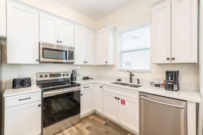 a kitchen with white cabinets and stainless steel appliances at Coral Cottage Near Disney With Margaritaville Resort & Island H2O Access - 8063Kd in Orlando
