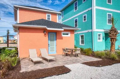 a patio with chairs and a table in front of a building at Coral Cottage Near Disney With Margaritaville Resort & Island H2O Access - 8063Kd in Orlando