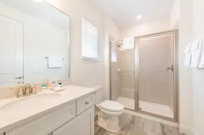 a white bathroom with a shower and a toilet at The Island Life! Near Disney With Margaritaville Resort & Island H2O Access - 8055Kd in Orlando