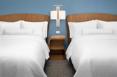 two beds in a hotel room with a nightstand between them at Element Orlando Universal Blvd. in Orlando