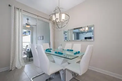 a dining room with a glass table and white chairs at 4834BV TOWNHOUSE 4 BEDROOMS & 3 BATHROOMS + POOL in Kissimmee