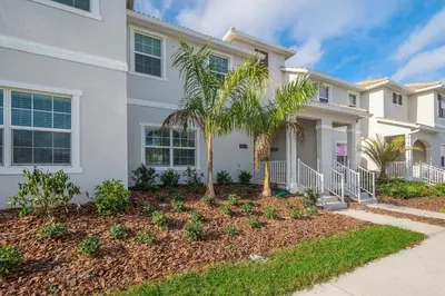 a white house with a palm tree in front of it at 4834BV TOWNHOUSE 4 BEDROOMS & 3 BATHROOMS + POOL in Kissimmee