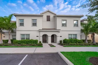 a large white house with palm trees at 4833NF TOWNHOUSE 4 BEDROOMS & 3 BATHROOMS + POOL in Kissimmee