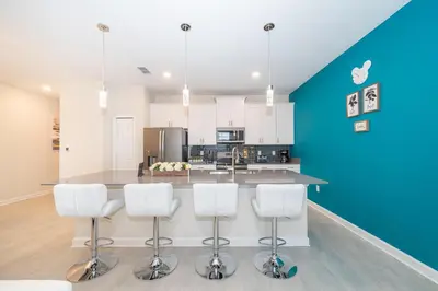 a kitchen with a counter with four bar stools at 4830FA TOWNHOUSE 4 BEDROOMS & 3 BATHROOMS + POOL in Kissimmee