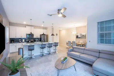 a living room with a couch and a kitchen at 4993FP TOWNHOUSE 4 BEDROOMS & 3 BATHROOMS + POOL in Kissimmee