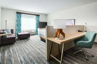 a hotel room with a desk and a bedroom at Hilton Garden Inn Apopka City Center, Fl in Orlando