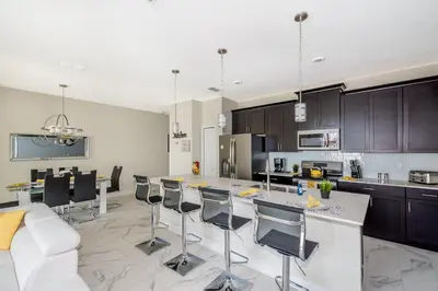 a large kitchen with a white counter and chairs at 4929GC TOWNHOUSE 4 BEDROOMS & 3 BATHROOMS + POOL in Kissimmee
