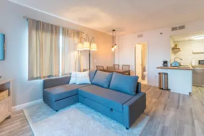 a living room with a blue couch and a kitchen at Deluxe Studio w/ Lakeview - free parking/pool in Orlando