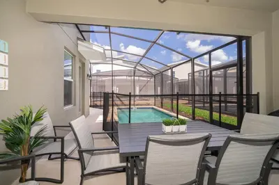 a patio with a table and chairs and a swimming pool at 2770AG VILLA 5 BED/5 BA (SANITIZED) in Kissimmee