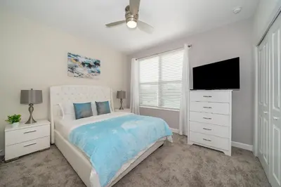 a white bedroom with a bed and a flat screen tv at 2738WE VILLA 5 BED/5 BA (SANITIZED) in Kissimmee
