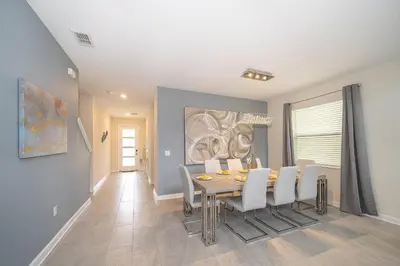 a dining room with a table and white chairs at 2744HM VILLA 5 BED/5 BA (SANITIZED) in Kissimmee