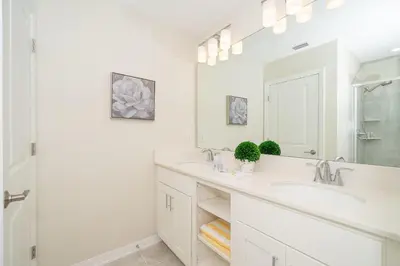 a white bathroom with two sinks and a mirror at 3111-302HM STOREY LAKE, CONDO 2/2 LAKE VIEW in Kissimmee