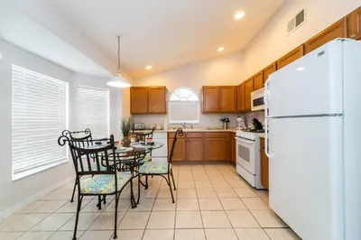 a kitchen with a table and chairs and a white refrigerator at 16150EGRET- Sun Chaser (S) in Orlando