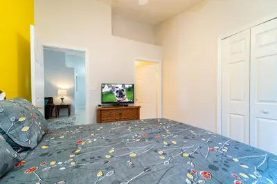 a bedroom with a bed with a blue comforter and a television at 16150EGRET- Sun Chaser (S) in Orlando
