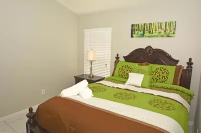 a bedroom with a large bed with green and brown sheets at 2685OL - Jagu Deaux (G) in Kissimmee