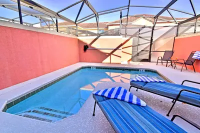 a swimming pool with two benches next to a building at 8975CPR - Waites Home (G) in Kissimmee