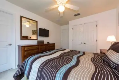a bedroom with a bed with a dresser and a mirror at Encantada 3 Bedroom Townhome with Pool 2009 in Kissimmee