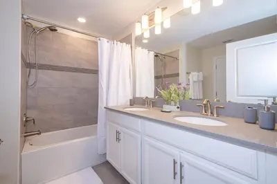a white bathroom with two sinks and a shower at 4819JA TOWNHOUSE 4 BEDROOMS & 3 BATHROOMS + POOL in Kissimmee