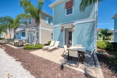 a patio with chairs and a table in front of a house at Celestial Cottage Near Disney With Margaritaville Resort & Island H2O Access - 8036Dr in Orlando