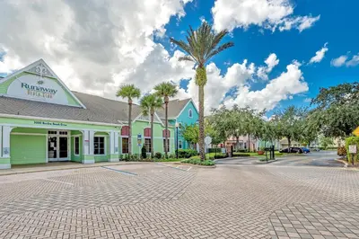 a building with a palm tree in front of a street at 2 Bedroom Vacation Condo 2011 in Kissimmee