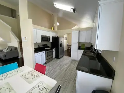 a kitchen with white cabinets and a table with a red chair at Platinum Vacation Homes of Orlando in Orlando