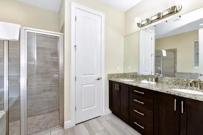 a bathroom with two sinks and a shower with a glass door at Amazing Home With Theme Rooms, Game Rooms Near Disney With Waterpark & Resort Access At Encore Resort - 7647Wl in Kissimmee
