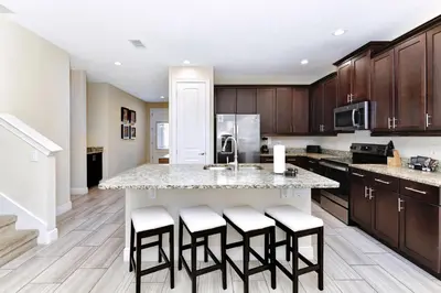 a kitchen with a large island with bar stools at Amazing Home With Theme Rooms, Game Rooms Near Disney With Waterpark & Resort Access At Encore Resort - 7647Wl in Kissimmee