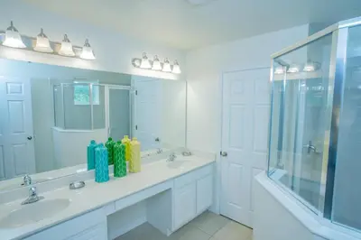 a white bathroom with two sinks and a shower at Fantastic 4br 3ba with Pvt Pool near to Disney in Kissimmee