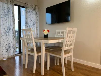 a dining room table with three chairs and a television at 18-Universal and Heart of International Dr in Orlando