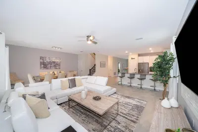a living room with white furniture and a kitchen at 2705JT LUXURY 7 BED/5 BA (SANITIZED) in Kissimmee
