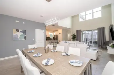 a dining room with a table and white chairs at 2776LO VILLA 5 BED/5 BA (SANITIZED) in Kissimmee