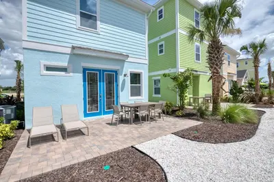 a patio with a table and chairs in front of a house at Sandy Shores Cottage Near Disney With Margaritaville Resort & Island H20 Waterpark Access - 2962Sr in Orlando