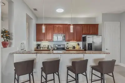 a kitchen with brown cabinets and a counter with bar stools at Vista Cay in Orlando