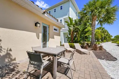 a patio with a table and chairs in front of a house at Sunny Cottage Near Disney With Margaritaville Resort & Island H2O Access - 8032Ls in Orlando