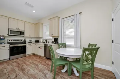 a kitchen with a white table and green chairs at Sunny Cottage Near Disney With Margaritaville Resort & Island H2O Access - 8032Ls in Orlando