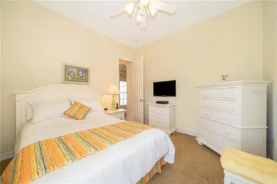 a white bedroom with a bed and a dresser at Mickeys Corner - Fantastic 5BR with Large Private Garden Pool Hot Tub Game Room Gas BBQ 2 Miles to Disney in Orlando
