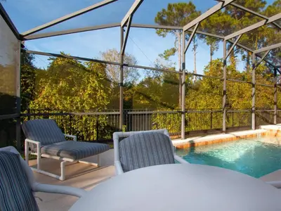 a patio with a table and chairs and a swimming pool at 4 Bed And 3 Bath In Perfect Location With Pool By Florida Dream Home in Kissimmee
