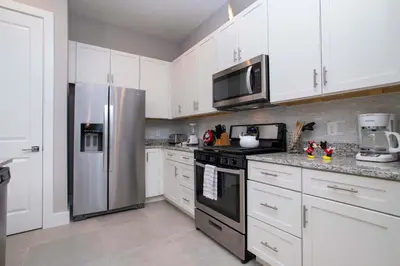a kitchen with white cabinets and a stainless steel refrigerator at Gorgeous 4 Bedroom Family Friendly Close to Disney 7573 in Orlando