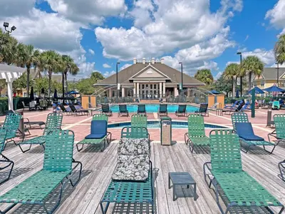 a pool with chaise lounge chairs and a swimming pool at Villas at Seven Dwarfs - Close to Disney in Kissimmee