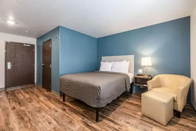 a bedroom with a bed and a chair in a room at WoodSpring Suites Sanford North I-4 Orlando Area in Sanford