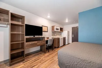 a hotel room with a bed and a desk with a television at WoodSpring Suites Sanford North I-4 Orlando Area in Sanford