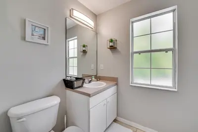 a bathroom with a toilet and a sink and a window at 8 Mi to Disney Villa with Screened Pool and Lanai in Kissimmee