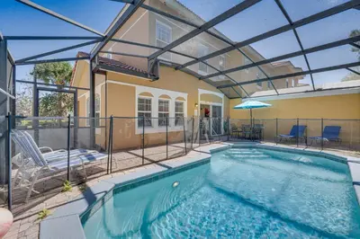 an indoor swimming pool with an umbrella and a house at 8 Mi to Disney Villa with Screened Pool and Lanai in Kissimmee