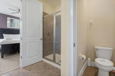 a bathroom with a toilet and a shower and a bed at 551 Villa 8BD PoolSpa - Game room Movie room in Orlando