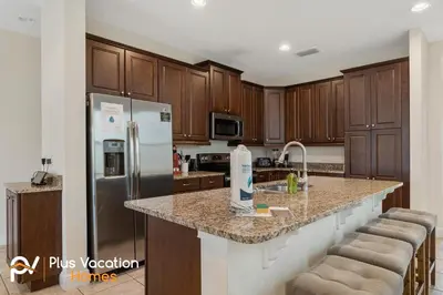 a kitchen with wooden cabinets and a stainless steel refrigerator at 331 Villa SpaPool- GamesTheater by Disney in Orlando