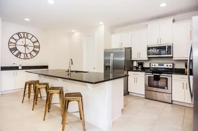 a kitchen with white cabinets and a large clock on the wall at Gorgeous Single Home with Private Pool at Encore in Orlando
