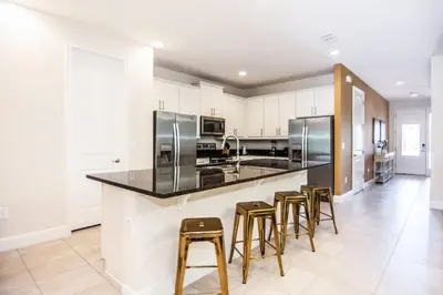 a kitchen with bar stools and stainless steel appliances at Gorgeous Single Home with Private Pool at Encore in Orlando