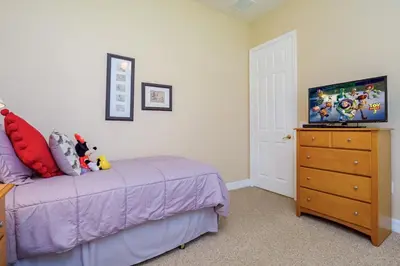 a bedroom with a bed and a dresser with a tv at Mickeys Floridian - Glorious 5BR Private South Facing Pool Hot Tub Game RM GYM BBQ - 2 miles to Disney in Orlando